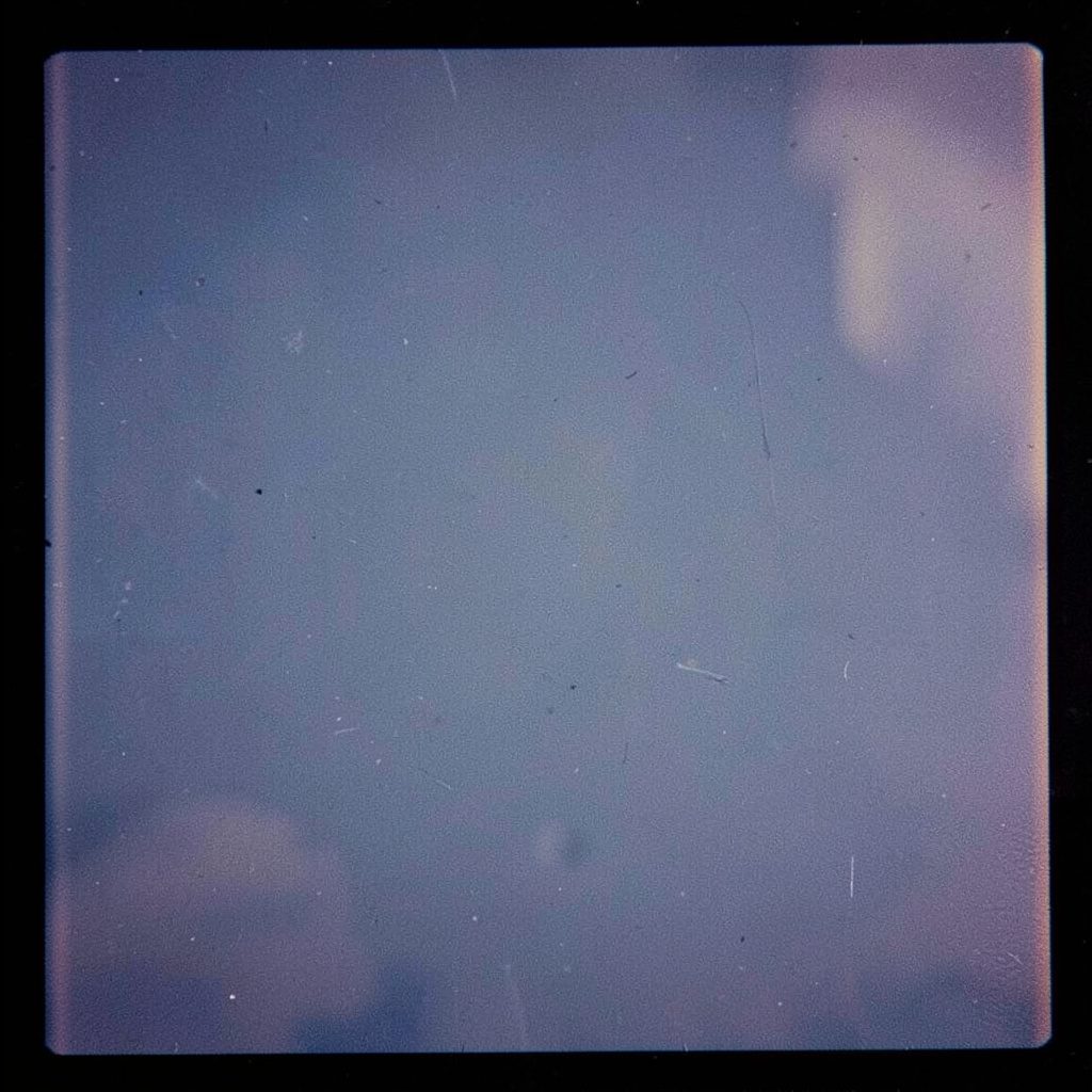 Analog film close-up of red apples in a wooden bowl, navy and steel-blue palette, gentle grain.